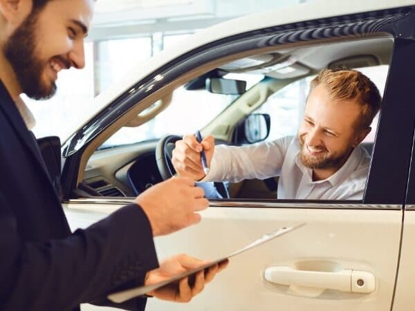 Immagine di un cliente soddisfatto che riceve le chiavi della sua auto da un professionista del servizio di rimessaggio auto, simboleggiando i vantaggi e la comodità di utilizzare un servizio di rimessaggio affidabile.