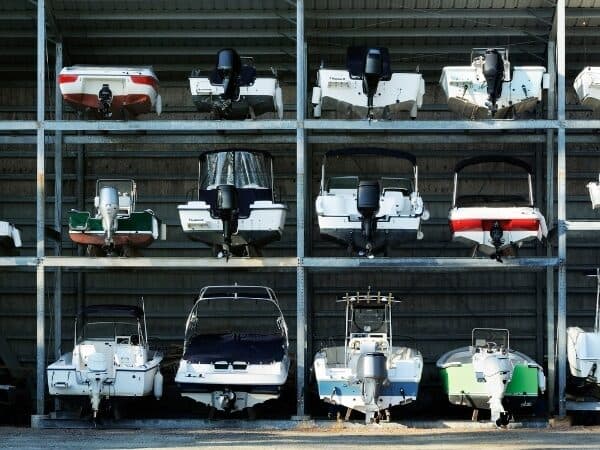 barche con i relativi motori fuoribordo, sistemate in modo ordinato in uno scaffale metallico multi-livello, tipico di un deposito per il rimessaggio barca a secco