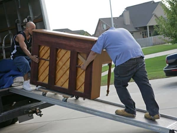 due uomini cercano di spedire un pianoforte su un furgone